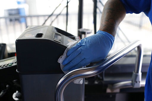 An Athens-Clarke County Transit worker cleans a bus meter at the Athens Transit Multimodal Center in downtown Athens, Ga., on Friday, March 13. 2020. Athens-Clarke County ramped-up it's cleaning procedures on March 3rd in preparation for the Coronavirus (COVID-19). (Joshua L. Jones/Athens Banner-Herald via AP)