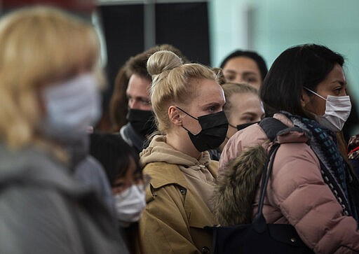 Passengers wearing masks line up as they wait to check in at Barcelona airport, Spain, Saturday, March 14, 2020. Spain's prime minister has announced a two-week state of emergency from Saturday in a bid to contain the new coronavirus outbreak. For most people, the new coronavirus causes only mild or moderate symptoms. For some, it can cause more severe illness, especially in older adults and people with existing health problems. (AP Photo/Emilio Morenatti)