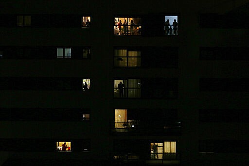 People applaud from their houses in support of the medical staff that are working in COVID-19 outbreak in Rivas Vaciamadrid, Spain, Saturday, March 14, 2020. Spanish Prime Minister Pedro Sanchez said his government will declare a two-week state of emergency on Saturday, giving itself extraordinary powers including the mobilization of the armed forces, to confront the COVID-19 outbreak. For some, especially older adults and people with existing health problems, it can cause more severe illness, including pneumonia. (AP Photo/Manu Fernandez)