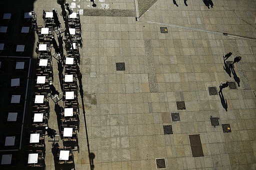 Pedestrians pass by an empty bar at Plaza del Castillo square, in Pamplona, northern Spain, Saturday, March 14, 2020. Spain's prime minister has announced a two-week state of emergency from Saturday in a bid to contain the new coronavirus outbreak.For most people, the new COVID-19 coronavirus causes only mild or moderate symptoms, such as fever and cough, but for some, especially older adults and people with existing health problems, it can cause more severe illness, including pneumonia. (AP Photo/Alvaro Barrientos)