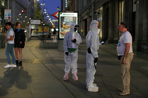 People wearing protective clothes talk with a man at the Gran Via avenue in downtown in Madrid, Spain, Saturday, March 14, 2020. Spanish Prime Minister Pedro Sanchez said his government will declare a two-week state of emergency on Saturday, giving itself extraordinary powers including the mobilization of the armed forces, to confront the COVID-19 outbreak. For some, especially older adults and people with existing health problems, it can cause more severe illness, including pneumonia. (AP Photo/Manu Fernandez)