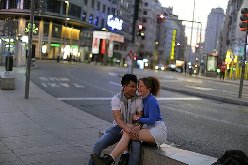 A couple enjoy a light moment at the Gran Via avenue in downtown in Madrid, Spain, Saturday, March 14, 2020. Spanish Prime Minister Pedro Sanchez said his government will declare a two-week state of emergency on Saturday, giving itself extraordinary powers including the mobilization of the armed forces, to confront the COVID-19 outbreak. For some, especially older adults and people with existing health problems, it can cause more severe illness, including pneumonia. (AP Photo/Manu Fernandez)