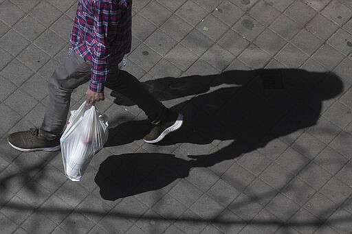 A man carries provisions in shopping bags from a supermarket in Madrid, Spain, Saturday, March 14, 2020. Spain's prime minister has announced a two-week state of emergency from Saturday in a bid to contain the new COVID-19 coronavirus outbreak. For most people, the new coronavirus causes only mild or moderate symptoms. For some, it can cause more severe illness, especially in older adults and people with existing health problems. (AP Photo/PW)