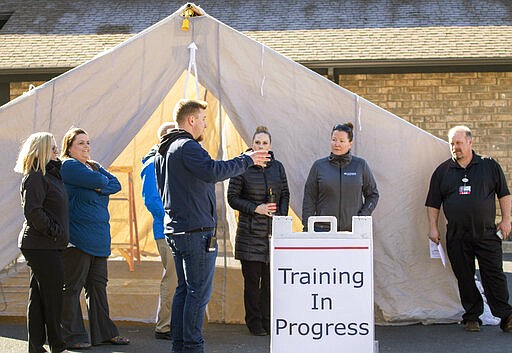 Director of Safety and Security Derec Styer, center, talks to other employees during an training session on Thursday, March 12, 2020, at Gritman Medical Center in Moscow, Idaho. The training allowed employees to practicing setting up a tent that can be used for drive-up non-emergency screening for COVID-19 coronavirus. (Geoff Crimmins/Moscow-Pullman Daily News via AP) (Geoff Crimmins/Moscow-Pullman Daily News via AP)