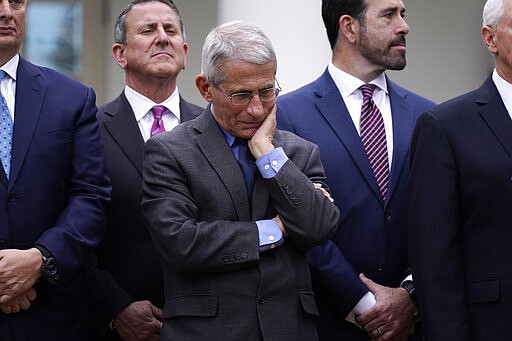 Dr. Anthony Fauci, director of the National Institute of Allergy and Infectious Diseases, center, listens during a news conference about the coronavirus in the Rose Garden of the White House, Friday, March 13, 2020, in Washington. (AP Photo/Evan Vucci)