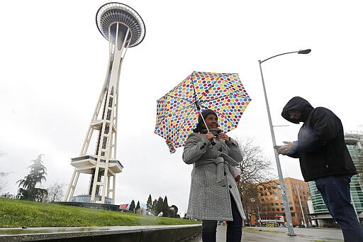 Aida Cruz, left, and Jose Chavez, take photos at the Space Needle, Friday, March 13, 2020, in Seattle. The two were visiting from San Antonio, Texas and had planned to take the elevator up the Needle for a view of the city, but they discovered that the iconic landmark and tourist attraction had closed Friday and will remain so through the end of March due to the outbreak of the COVID-19 coronavirus in Washington state.  The vast majority of people recover from the new coronavirus. According to the World Health Organization, most people recover in about two to six weeks, depending on the severity of the illness. (AP Photo/Ted S. Warren)