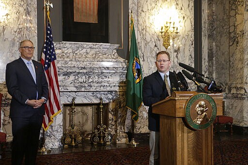 State Superintendent of Public Instruction Chris Reykdal, right, talks to the media about the decision to close all schools in the state in response to COVID-19, as Gov. Jay Inslee looks on, Friday, March 13, 2020, in Olympia, Wash. Inslee issued an executive order expanding the closures from three counties to all 39, saying the virus is spreading rapidly across the state. (AP Photo/Rachel La Corte)