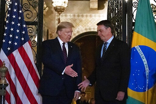 FILE - In this March 7, 2020, file photo President Donald Trump shakes hands before a dinner with Brazilian President Jair Bolsonaro at Mar-a-Lago in Palm Beach, Fla. Bolsonaro&#146;s communications director, F&aacute;bio Wajngarten, tested positive just days after traveling with Bolsonaro to a meeting with Trump and senior aides in Florida. (AP Photo/Alex Brandon, File)