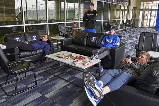 In this March 13, 2020 photo, Creighton NCAA college baseball pitchers Ben Dotzler, top center, and Tommy Steier, second right, watch President Trump declare a national emergency to combat the coronavirus pandemic, in the player lounge in Omaha, Neb. Dotzler was supposed to be in the bullpen at TD Ameritrade Park this weekend readying himself to pitch against Northern Colorado, Everything changed for hm and thousands of other college athletes when the NCAA announced March 12, 2020, it was canceling all spring sports championships, along with remaining winter championships, as a precaution against the spread of the new coronavirus.  (AP Photo/Nati Harnik)