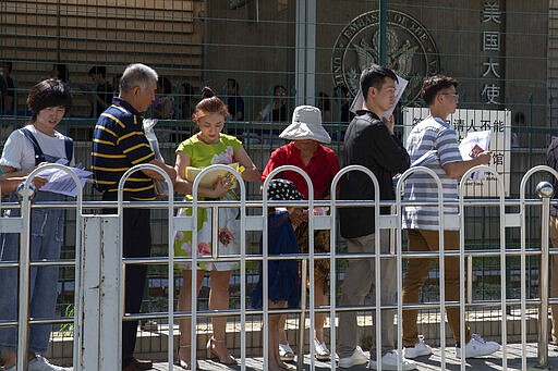 In this July 26, 2018, photo, visa applicants queue up to enter the U.S. embassy consulate section in Beijing. After American consulates in China suspended visa processing amid the coronavirus outbreak, hundreds of Chinese citizens applying for U.S. work visas have been stuck in limbo, fretting as crucial deadlines loom and their jobs in America look increasingly at risk. (AP Photo/Ng Han Guan)