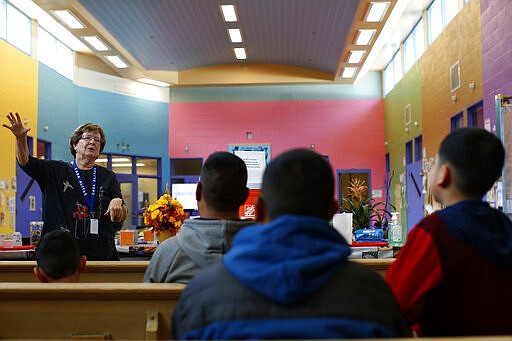 Volunteer Susan Gallegos talks to newly arrived asylum seekers from Central America at Casa Alitas, a Catholic-run shelter in Tucson, Ariz., Friday, Feb. 21, 2020. In numerous cities along the border with Mexico, Catholic-run agencies are outspoken advocates for migrants and asylum seekers hoping to reach the U.S. (AP Photo/Dario Lopez-MIlls)