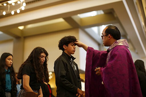 A priest marks repentance ashes on the foreheads of students from the St. John Paul II Catholic High School during Ash Wednesday Mass at the St. Thomas Aquinas church in Phoenix, Ariz., on Feb. 26, 2020. (AP Photo/Dario Lopez-MIlls)