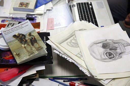 Books and drawings lie on the desk of an art teacher at the St. John Paul II Catholic School in Phoenix, Ariz., on Feb. 26, 2020. In the western suburbs of Phoenix, enrollment is surging at this new Catholic high school built to serve a fast-growing, heavily Hispanic community. (AP Photo/Dario Lopez-MIlls)