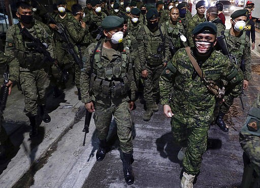 Filipino troopers wear protective masks as they arrive to augment police at Valenzuela, metropolitan Manila, Philippines early Sunday March 15, 2020. Thousands of Philippine police, backed by the army and coast guard, have started sealing the densely populated capital from most domestic travelers in one of Southeast Asia's most drastic containment moves against the coronavirus. For most people, the new coronavirus causes only mild or moderate symptoms. For some, it can cause more severe illness, especially in older adults and people with existing health problems. (AP Photo/Aaron Favila)