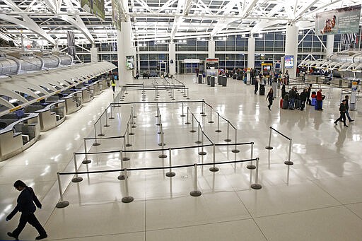 People visit an international terminal at John F. Kennedy airport, Friday, March 13, 2020, in New York. A ban on travelers from most European countries begins at midnight Friday, and travelers returning from there will be screened. The ban is the latest calamity for a global travel industry already reeling from falling bookings and canceled reservations as people try to avoid contracting and spreading the coronavirus. (AP Photo/Kathy Willens)