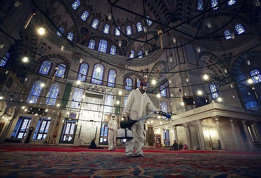 A worker wearing protective clothing disinfects historical Fatih Mosque, in Istanbul, Saturday, March 14, 2020, as a precaution against the coronavirus. For most people, the new coronavirus causes only mild or moderate symptoms. For some it can cause more severe illness.(AP Photo/Emrah Gurel)