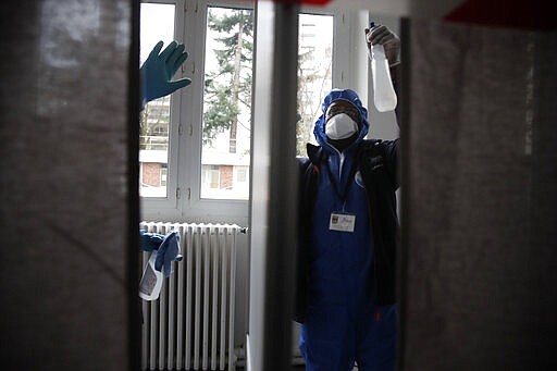 Workers wearing protective gears uses disinfectant to clean a voting booth as a precautionary measure against COVID-19 on the eve of the municipal elections in a Neuilly-sur-Seine polling station, outside Paris, Saturday, March 14, 2020. For most people, the new coronavirus causes only mild or moderate symptoms. For some it can cause more severe illness, especially in older adults and people with existing health problems. (AP Photo/Christophe Ena)