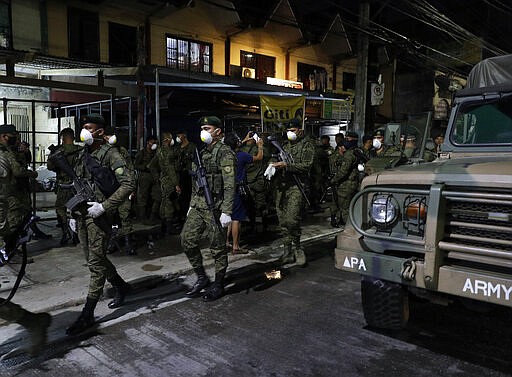 Filipino army troopers, some wearing protective masks, arrive to augment police in Valenzuela, metropolitan Manila, Philippines early Sunday March 15, 2020. Thousands of Philippine police, backed by the army and coast guard, have started sealing the densely populated capital from most domestic travelers in one of Southeast Asia's most drastic containment moves against the coronavirus. For most people, the new coronavirus causes only mild or moderate symptoms. For some, it can cause more severe illness, especially in older adults and people with existing health problems. (AP Photo/Aaron Favila)