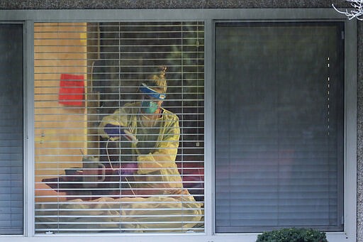 A nurse works in the room of Chuck Sedlacek &#151; who has tested positive for the COVID-19 coronavirus &#151; Friday, March 13, 2020, as seen through the window of his room at Life Care Center in Kirkland, Wash., near Seattle. The facility has been at the center of the coronavirus outbreak in the state, and Sedlacek's son Scott Sedlacek said that he and his siblings have barely spoken to their father inside the center, who in addition to testing positive for the coronavirus, has blindness, neuropathy, and has difficulty using a phone, saying he is more of an &quot;inmate&quot; than a patient. Residents of assisted living facilities and their loved ones are facing a grim situation as the coronavirus spreads across the country, placing elderly people especially at risk. (AP Photo/Ted S. Warren)