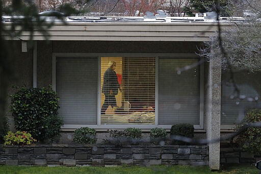 A nurse wearing a mask walks past the room of Chuck Sedlacek &#151; who has tested positive for the COVID-19 coronavirus &#151; Friday, March 13, 2020, as seen through the window of his room at Life Care Center in Kirkland, Wash., near Seattle. The facility has been at the center of the coronavirus outbreak in the state, and Sedlacek's son Scott Sedlacek said that he and his siblings have barely spoken to their father inside the center, who in addition to testing positive for the coronavirus, has blindness, neuropathy, and has difficulty using a phone, saying he is more of an &quot;inmate&quot; than a patient. Residents of assisted living facilities and their loved ones are facing a grim situation as the coronavirus spreads across the country, placing elderly people especially at risk. (AP Photo/Ted S. Warren)