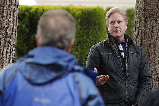 In this March 12, 2020, photo, Scott Sedlacek, left, who has tested positive for the COVID-19 coronavirus, listens as Tim Killian, right, a spokesman for Life Care Center in Kirkland, Wash., answers one of Sedlacek's questions during Killian's daily press briefing. Sedlacek's father, Chuck, who also has tested positive, lives in the facility, which has been at the center of the COVID-19 coronavirus outbreak in the state, and Sedlacek said he and his siblings have barely spoken to their father, who has blindness and neuropathy, and difficulty using a phone, saying he is more of an &quot;inmate&quot; than a patient. Residents of assisted living facilities and their loved ones are facing a grim situation as the coronavirus spreads across the country, placing elderly people especially at risk. (AP Photo/Ted S. Warren)