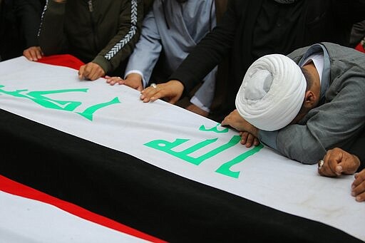 Mourners and militia fighters mourn by the flag-draped coffins of two fighters of the Popular Mobilization Forces who were killed during the US attack on against militants in Iraq, during their funeral procession at the Imam Ali shrine in Najaf, Iraq, Saturday, March 14, 2020. The U.S. launched airstrikes on Thursday in Iraq, targeting the Iranian-backed Shiite militia members believed responsible for a rocket attack that killed and wounded American and British troops at a base north of Baghdad. (AP Photo/Anmar Khalil)