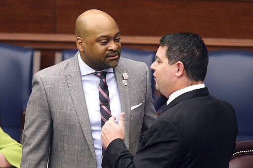 Sen. Oscar Braynon, D-Miami Gardens, left, confers with Sen. Travis Hutson, R-St. Augustine, during session Friday March 13, 2020 in Tallahassee, Fla. (AP Photo/Steve Cannon)