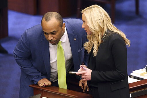 Sen. Lauren Book, D-Plantation, left, confers with Sen. Bobby Powell, D-West Palm Beach, during session Friday March 13, 2020 in Tallahassee, Fla. (AP Photo/Steve Cannon)