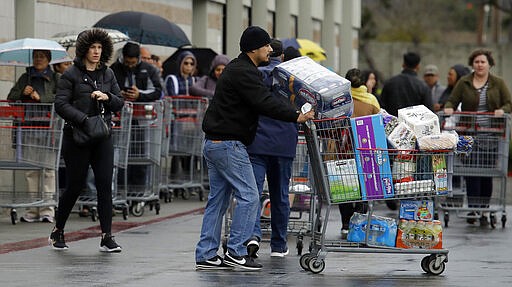 Costco customers roll groceries to their cars as others wait to enter the store on Saturday, March 14, 2020, in San Leandro, Calif. Empty store shelves. Empty churches. Shuttered classrooms and courts. Warnings everywhere to wash hands and avoid close contact.  Efforts to stop the spread of the coronavirus in California are affecting virtually every facet of life in the Golden State in ways big and small &#151; and in some cases, surreal. For most people, the new coronavirus causes only mild or moderate symptoms. For some it can cause more severe illness. (AP Photo/Ben Margot)