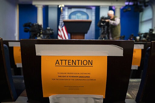 Signs in the briefing room of the White House indicate social distancing measures being taken to separate reporters working at the White House, Monday, March 16, 2020, in Washington. (AP Photo/Evan Vucci)