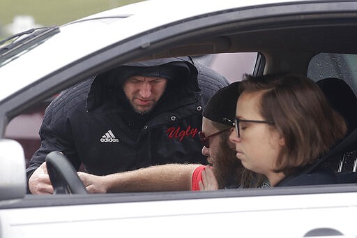 Executive pastor Jason Bishop, rear, closes his eyes while delivering drive up prayer service to Samantha Ferro, right, and Bobby Hallman in their car outside of The Bay Church in Concord, Calif., Sunday, March 15, 2020. (AP Photo/Jeff Chiu)