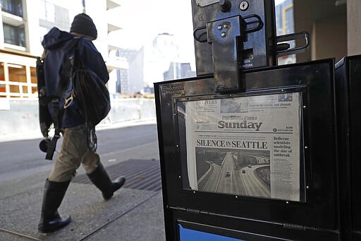 A man walks near a Seattle Times newspaper box in front of the building that houses the Times' newsroom, Sunday, March 15, 2020 in Seattle, as the headline &quot;Silence in Seattle&quot; is displayed. Washington Gov. Jay Inslee said Sunday night that he would order all bars, restaurants, entertainment and recreation facilities in the state to temporarily close to fight the spread of coronavirus, as Washington state has by far the most deaths in the U.S. from the disease. (AP Photo/Ted S. Warren)