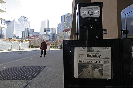 A woman walks near a Seattle Times newspaper box in front of the building that houses the Times' newsroom, Sunday, March 15, 2020 in Seattle, as the headline &quot;Silence in Seattle&quot; is displayed. Washington Gov. Jay Inslee said Sunday night that he would order all bars, restaurants, entertainment and recreation facilities in the state to temporarily close to fight the spread of coronavirus, as Washington state has by far the most deaths in the U.S. from the disease. (AP Photo/Ted S. Warren)