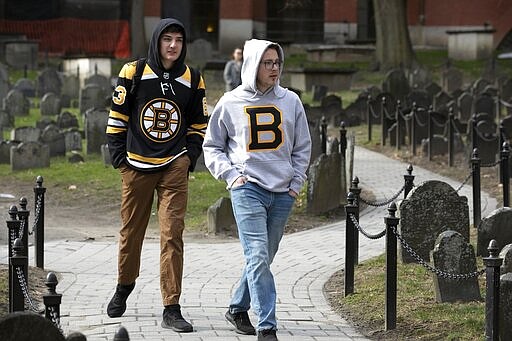 Matthew Hammerschmidt, right, and Dasan Zahn, both of Bismarck, N.D., visit Old Granary Burying Ground in Boston, Saturday, March, 14, 2020. Fans of the Boston Bruins, they had flown in specifically for Saturday night's game against the Toronto Maple Leafs. The pair said they learned that the NHL had suspended play due to concern about the coronavirus just as the plane was touching down in Boston. For most people, the new coronavirus causes only mild or moderate symptoms, such as fever and cough. For some, especially older adults and people with existing health problems, it can cause more severe illness, including pneumonia. The vast majority of people recover from the new virus. (AP Photo/Michael Dwyer)