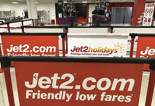 Empty check-in desks at the Jet2 desk at Edinburgh Airport, Scotland, Saturday March 14, 2020.  British budget airline Jet2 apparently turned back in midair all its planes bound for Spain on Saturday as it announced the cancellation of all its flights to the country.  (Andrew Milligan/PA via AP)