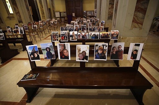 Selfies sent by parishioners lie on the benches of the Robbiano church as Masses for the faithful have been suspended following Italy's coronavirus emergency, in Giussano, northern Italy, Sunday, March 15, 2020.  For most people, the new coronavirus causes only mild or moderate symptoms. For some, it can cause more severe illness, especially in older adults and people with existing health problems. (AP Photo/Luca Bruno)