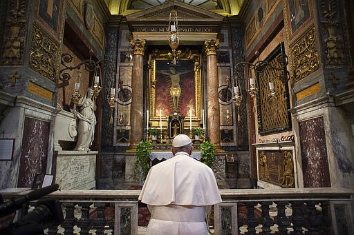 Pope Francis prays in S. Marcello al Corso church, in front of a miraculous crucifix that in 1552 was carried in a procession around Rome to stop the great plague, Sunday, March 15, 2020. For most people, the new coronavirus causes only mild or moderate symptoms. For some, it can cause more severe illness, especially in older adults and people with existing health problems. (Vatican News via AP)