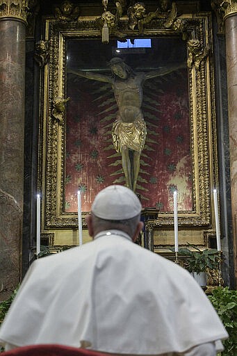 Pope Francis prays in S. Marcello al Corso church, in front of a miraculous crucifix that in 1552 was carried in a procession around Rome to stop the great plague, Sunday, March 15, 2020. For most people, the new coronavirus causes only mild or moderate symptoms. For some, it can cause more severe illness, especially in older adults and people with existing health problems. (Vatican News via AP)