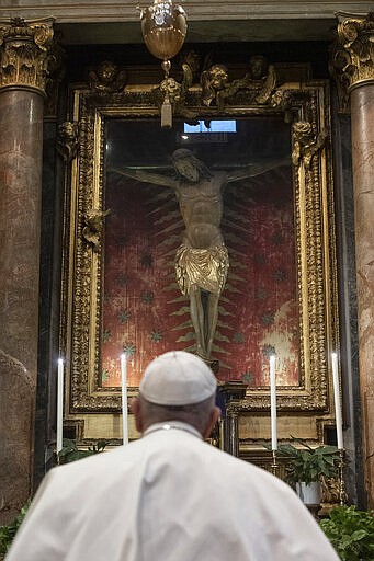 Pope Francis prays in S. Marcello al Corso church, in front of a miraculous crucifix that in 1552 was carried in a procession around Rome to stop the great plague, Sunday, March 15, 2020. For most people, the new coronavirus causes only mild or moderate symptoms. For some, it can cause more severe illness, especially in older adults and people with existing health problems. (Vatican News via AP)