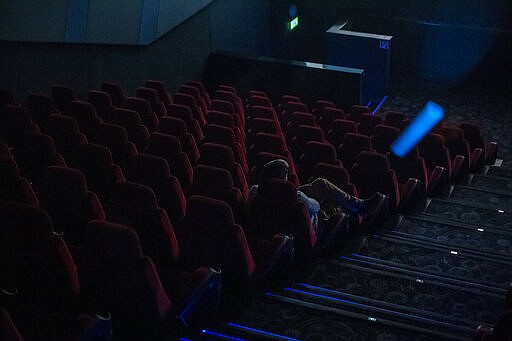 A sole spectator watches a film in a movie theatre in Budapest, Hungary, Thursday, March 12, 2020. Effective from today, cinemas in Hungary are restricted to sell a maximum of 99 tickets for a show as the Hungarian government declared a state of emergency in response to the novel coronavirus, and prohibited all indoor events with more than 100 participants and outdoor events attended by more than 500 participants. (Marton Monus/MTI via AP)