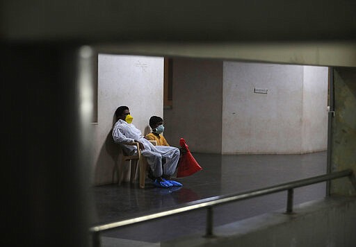 An Indian patient and his attendant wait at a Corona virus help desk at the Government Gandhi Hospital in Hyderabad, India, Sunday, March 15, 2020. For most people, the new coronavirus causes only mild or moderate symptoms. For some, it can cause more severe illness, especially in older adults and people with existing health problems. (AP Photo/Mahesh Kumar A.)