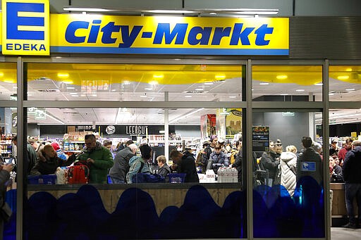 People shop in a supermarket in Berlin, Germany, Sunday, March 15, 2020. For most people, the new coronavirus causes only mild or moderate symptoms, such as fever and cough. For some, especially older adults and people with existing health problems, it can cause more severe illness, including pneumonia.(AP Photo/Markus Schreiber)