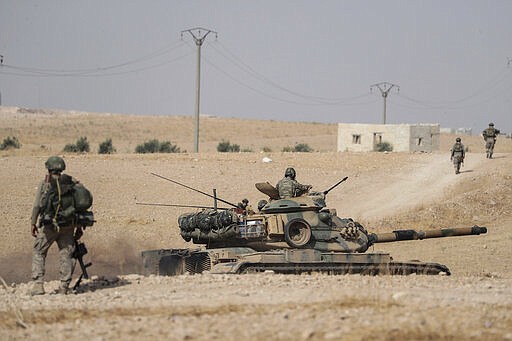 FILE - In this Oct. 15, 2019 file photo, Turkish tanks and troops stationed near Syrian town of Manbij, Syria. In a world gripped by a pandemic, global unrest and a fast-moving news cycle, it can be difficult to remember that the war in Syria is still happening. (Ugur Can/DHA via AP, File)