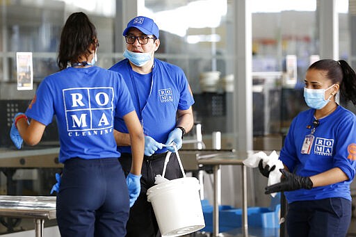 A cleaning crew works at a Transportation Security Administration checkpoint, Saturday, March 14, 2020, inside the jetBlue terminal at John F. Kennedy International Airport in New York. As the global viral pandemic grows, the need for cleaning and disinfecting has surged. Cleaners and domestic workers are essential in the effort to contain the virus. (AP Photo/Kathy Willens)