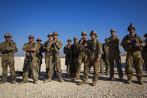 FILE - In this Monday, Nov. 11, 2019, file photo, crewmen of Bradley fighting vehicles stand guard at a U.S. military base in Northeastern Syria. In a world gripped by a pandemic, global unrest and a fast-moving news cycle, it can be difficult to remember that the war in Syria is still happening. (AP Photo/Darko Bandic, File)