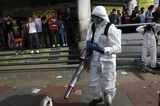 Firefighters prepare their fogging machines to disinfect a street against the new coronavirus as people watch, in western Tehran, Iran, Friday, March 13, 2020. The new coronavirus outbreak has reached Iran's top officials, with its senior vice president, Cabinet ministers, members of parliament, Revolutionary Guard members and Health Ministry officials among those infected.  The vast majority of people recover from the new coronavirus. According to the World Health Organization, most people recover in about two to six weeks, depending on the severity of the illness.  (AP Photo/Vahid Salemi)