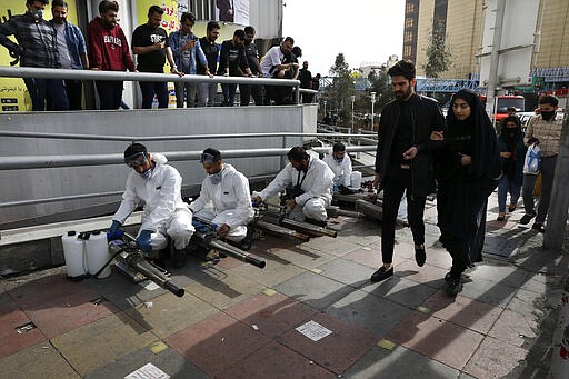 Firefighters prepare their fogging machines to disinfect a street against the new coronavirus as some people watch and pedestrians walk, in western Tehran, Iran, Friday, March 13, 2020. The new coronavirus outbreak has reached Iran's top officials, with its senior vice president, Cabinet ministers, members of parliament, Revolutionary Guard members and Health Ministry officials among those infected. The vast majority of people recover from the new coronavirus. According to the World Health Organization, most people recover in about two to six weeks, depending on the severity of the illness.  (AP Photo/Vahid Salemi)