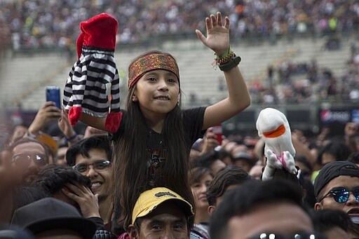 A girl holds a hand puppet as she watches Bersuit Vergarabat perform at the Vive Latino music festival,  in Mexico City, Saturday, March 14, 2020.  (AP Photo/Christian Palma)