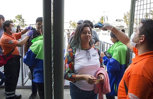 Health workers measure the temperature of music fans as a precaution against the spread of the new coronavirus, at the entrance gates of the venue for the Vive Latino Music Festival, in Mexico City, Saturday, March 14, 2020. On Friday afternoon organizers confirmed that the 21st edition of the festival will go on as planned. However, preventive measures will be taken, such as checking the temperature of the attendees upon admission and providing antibacterial gel. (AP Photo/Christian Palma)