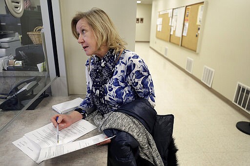 In this Thursday, Jan. 16, 2020 photo Jo Goode, city hall reporter for The Herald News of Fall River, Mass., picks up documents, at Fall River City Hall. Goode, who had reported extensively on the Fall River mayor's indictment on federal extortion charges, didn't expect that in 2018 the mayor would create an anonymous website, with her name as the address, featuring an endless loop of a video clip of President Donald Trump saying &quot;You are fake news!&quot; (AP Photo/Steven Senne)